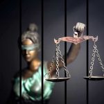 Wealthy Grandmother’s SHOCKING Murder Sentence Blindfolded Lady Justice statue holding scales behind bars.