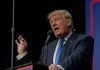 Trump Banner Sparks SHOCKING Gunfire Showdown Person speaking into microphone at a podium.