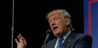 Trump Banner Sparks SHOCKING Gunfire Showdown Person speaking into microphone at a podium.