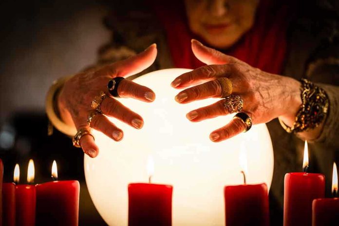 A person with adorned hands hovering over a glowing crystal ball surrounded by candles