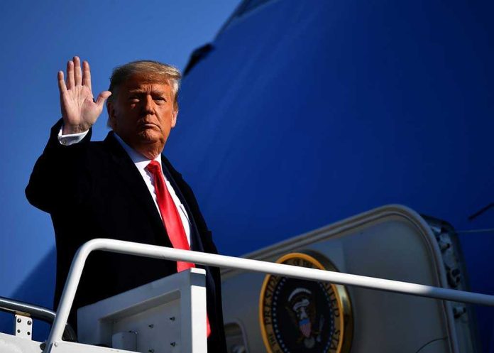 shutterstock_1898586520.jpg A political figure waving while standing on the steps of airforce one
