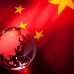 A globe illuminated against the backdrop of the Chinese flag