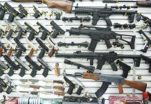 Shocking Lawsuit Blitz—Could Gun Companies Go Extinct? Wall display of various firearms in a store.