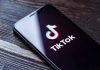 Viral TikTok Trend Sparks Fear – Are You Being Watched? Phone screen showing TikTok logo and app.