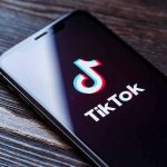 Phone screen showing TikTok logo and app.