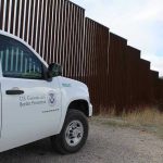 Military SWARM Hits Border—Nobody Ready for This Border protection vehicle near a large metal fence.