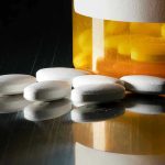 TV Show Triggers Shocking Surge in Drug Trend White pills beside an orange pill bottle.