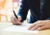 Person signing a document with a pen.