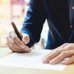 Person signing a document with a pen.
