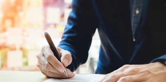 Person signing a document with a pen.