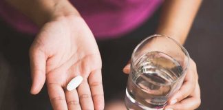 Person holding pill and glass of water