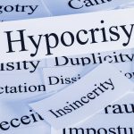 A collection of paper cards with various negative terms, prominently featuring the word Hypocrisy