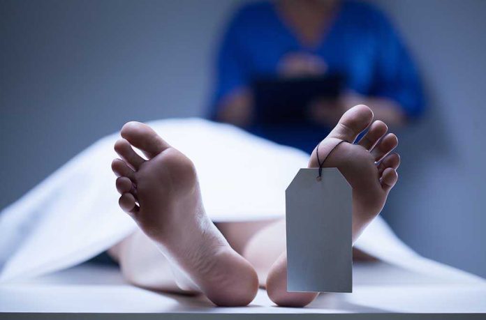 shutterstock_210811072.jpg A deceased body on a table with a tag on the foot, and a medical professional in the background