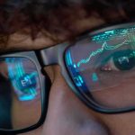 Close-up of a persons eyes with financial data reflected in their glasses