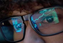 Close-up of a persons eyes with financial data reflected in their glasses