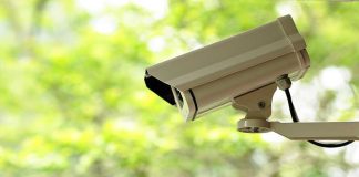 A security camera mounted outdoors with a blurred green background