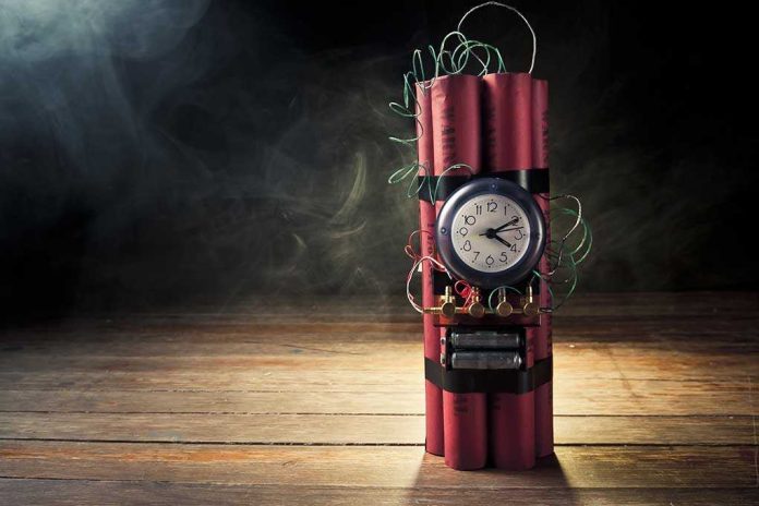 shutterstock_87180130.jpg A stick of dynamite with a clock timer and wires, set against a dark smoky background