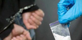 Shocking Arrests: Fentanyl and Ghost Guns Found Person handcuffed, police holding bag of white substance.