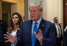 TRUMP Backs Controversial Military Decision Man speaking with hands raised, woman and security behind.