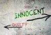 Graffiti on a wall depicting the words 'INNOCENT' and 'GUILTY' with arrows