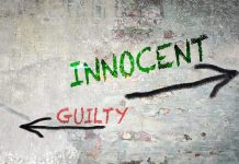Graffiti on a wall depicting the words 'INNOCENT' and 'GUILTY' with arrows