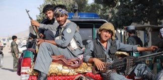 HORRIFYING Taliban Child Execution Shocks World Three armed soldiers sitting on the back of a military vehicle in an urban setting