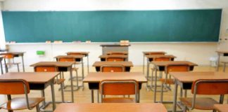 Conservative Teacher Fired Empty classroom with desks and a chalkboard.