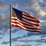 American flag waving against cloudy sky.