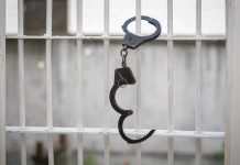 8 Inmates VANISH! Handcuffs hanging on white metal bars.