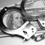 Slavery System Is Back Handcuffs placed over a stack of hundred dollar bills