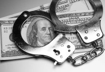 Handcuffs placed over a stack of hundred dollar bills