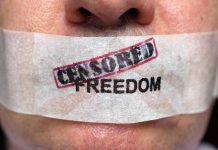 Close-up of a persons mouth covered with tape that reads CENSORED FREEDOM