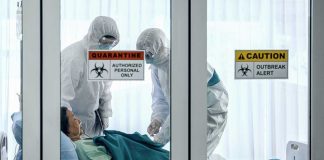 Ebola ‘Emergency’—Power Grab Warning Healthcare workers in protective gear in quarantine room.