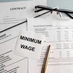 Documents and glasses on table with Minimum Wage paper.