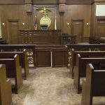Supreme Court DUCKS Deadly IQ Ruling Interior view of an empty courtroom with wooden benches and a judges bench