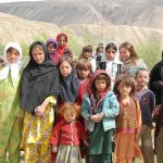 Group of children in colorful traditional clothing posing outdoors with mountains in the background