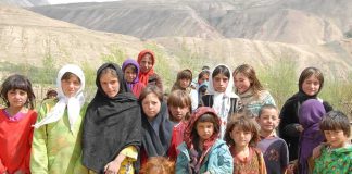 Group of children in colorful traditional clothing posing outdoors with mountains in the background