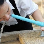 Person drinking water from a public fountain spout