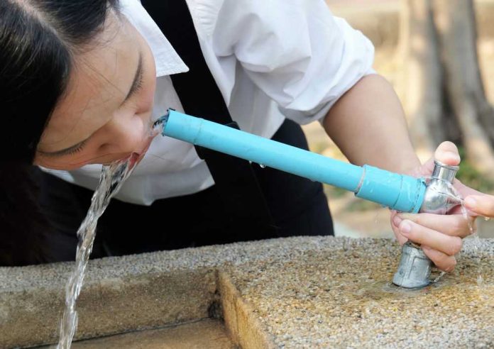 Person drinking water from a public fountain spout