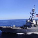 A naval destroyer sailing in the ocean with an American flag
