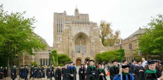 Lawsuit Targets University Over Pronoun Mandate Claims Graduates and faculty in academic regalia walking on a university campus