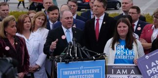 Coverage War Erupts Over Angel Families Group of people at a press conference with microphones and protest signs