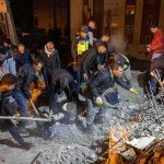 Rescue workers search through rubble at night