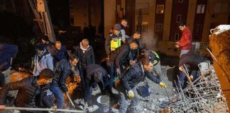 Rescue workers search through rubble at night