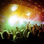 crowd at indoor concert with confetti and bright stage lights