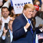 Trump’s Endorsement Delivers Another MAJOR WIN! man in suit raising fists at a rally podium