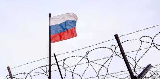 Russia Strikes Deal to Keep Military Foothold in Post-Assad Syria Russian flag behind barbed wire fence
