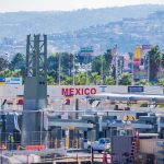 Border crossing booths at Mexico entry point with cityscape in background