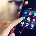 EU’s Social Media Ban Could Bring ID Checks for Adults Finger tapping smartphone social media app icons.