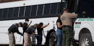 Border patrol officers investigating people near a bus.
